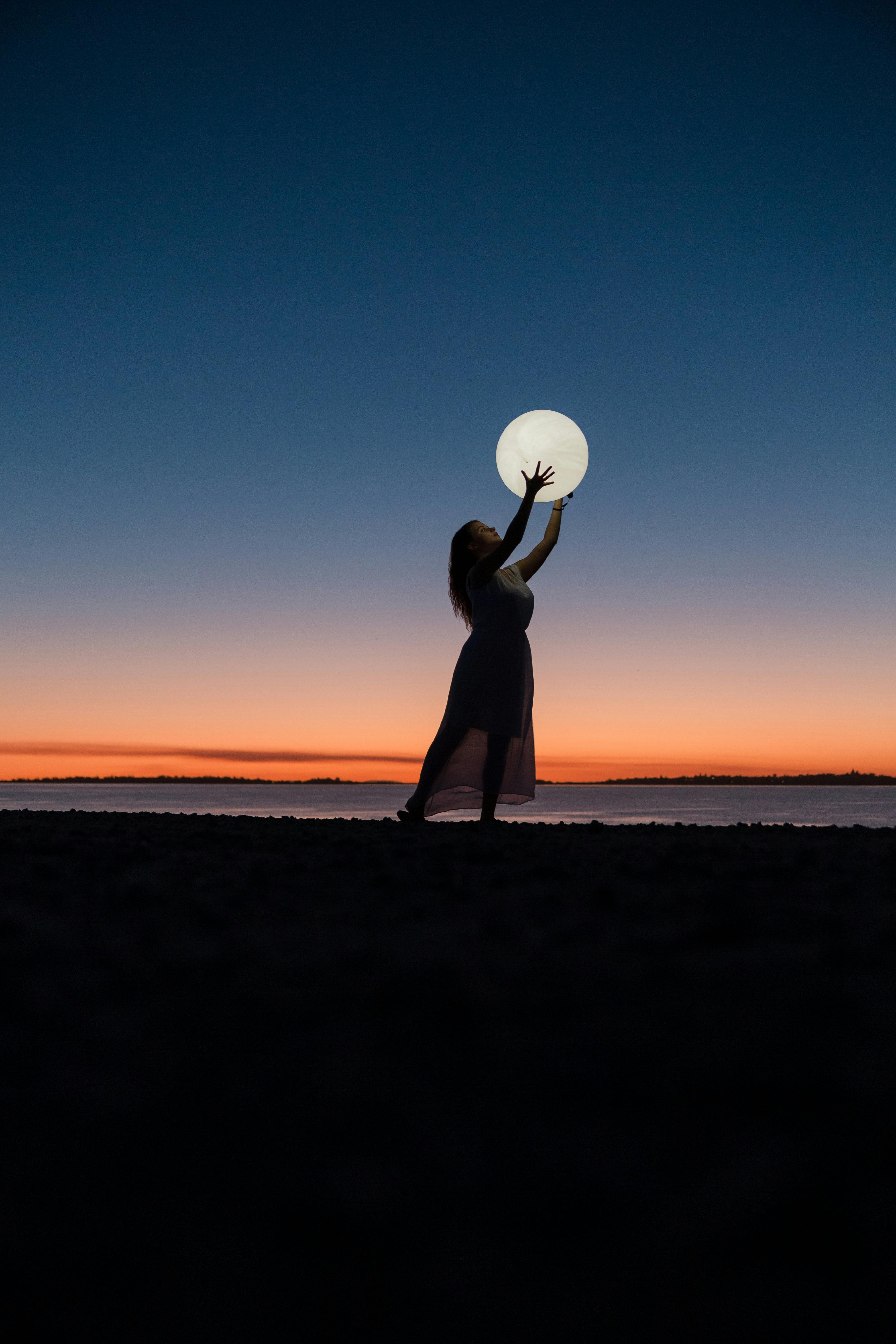 Woman Holding Moon At Dusk