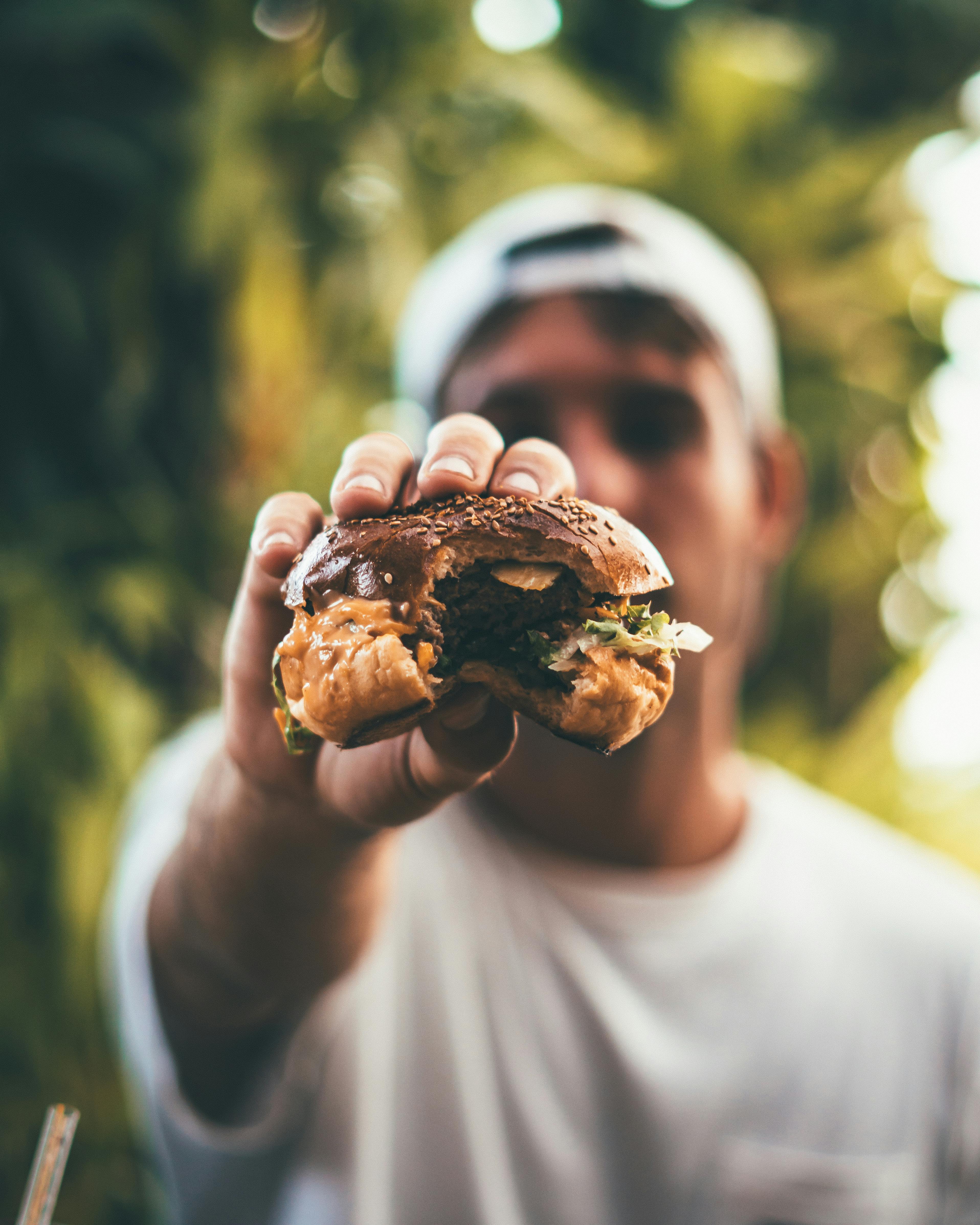 Bitten Burger Held Toward Camera — Food