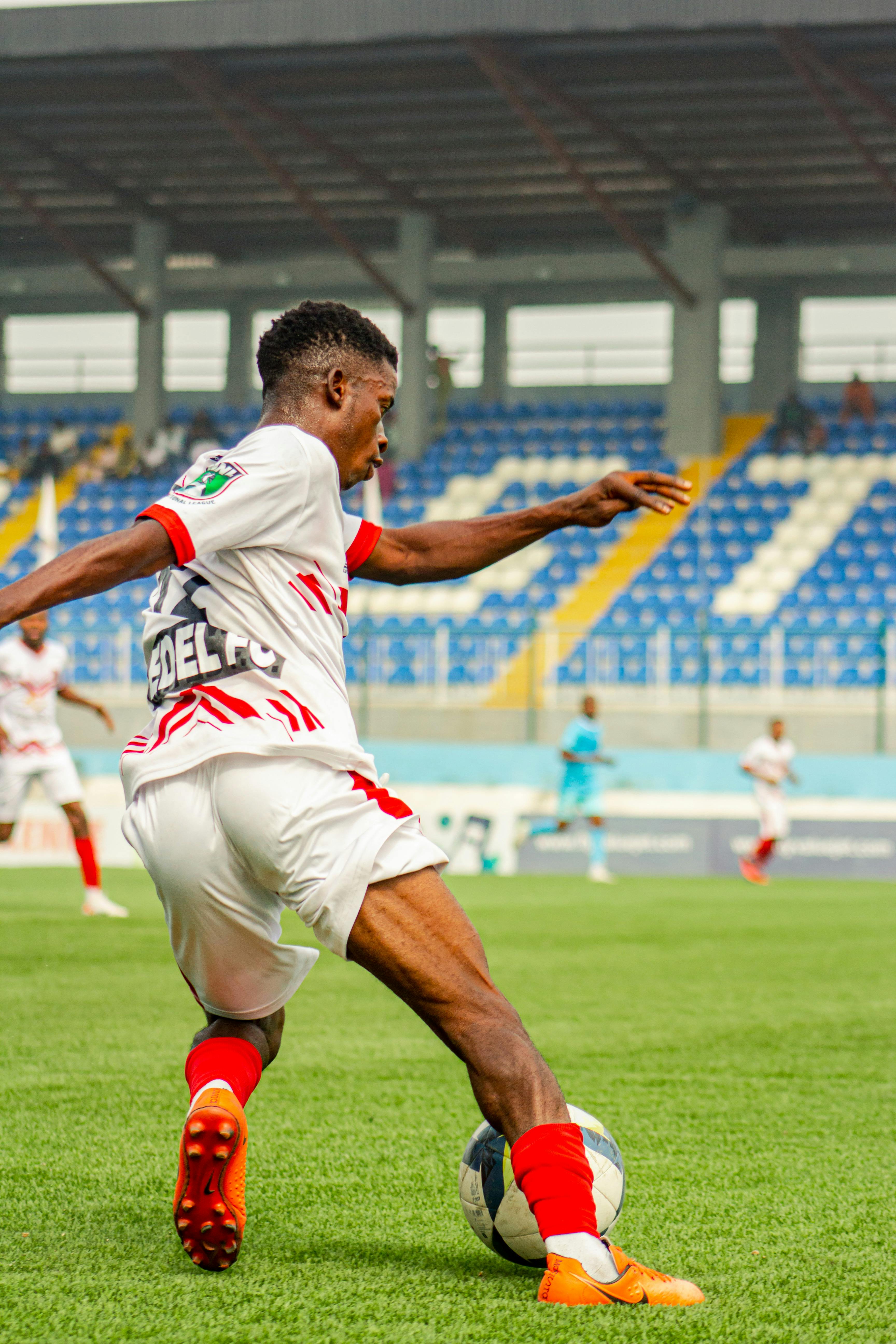 Soccer Player Dribbling on Stadium Pitch