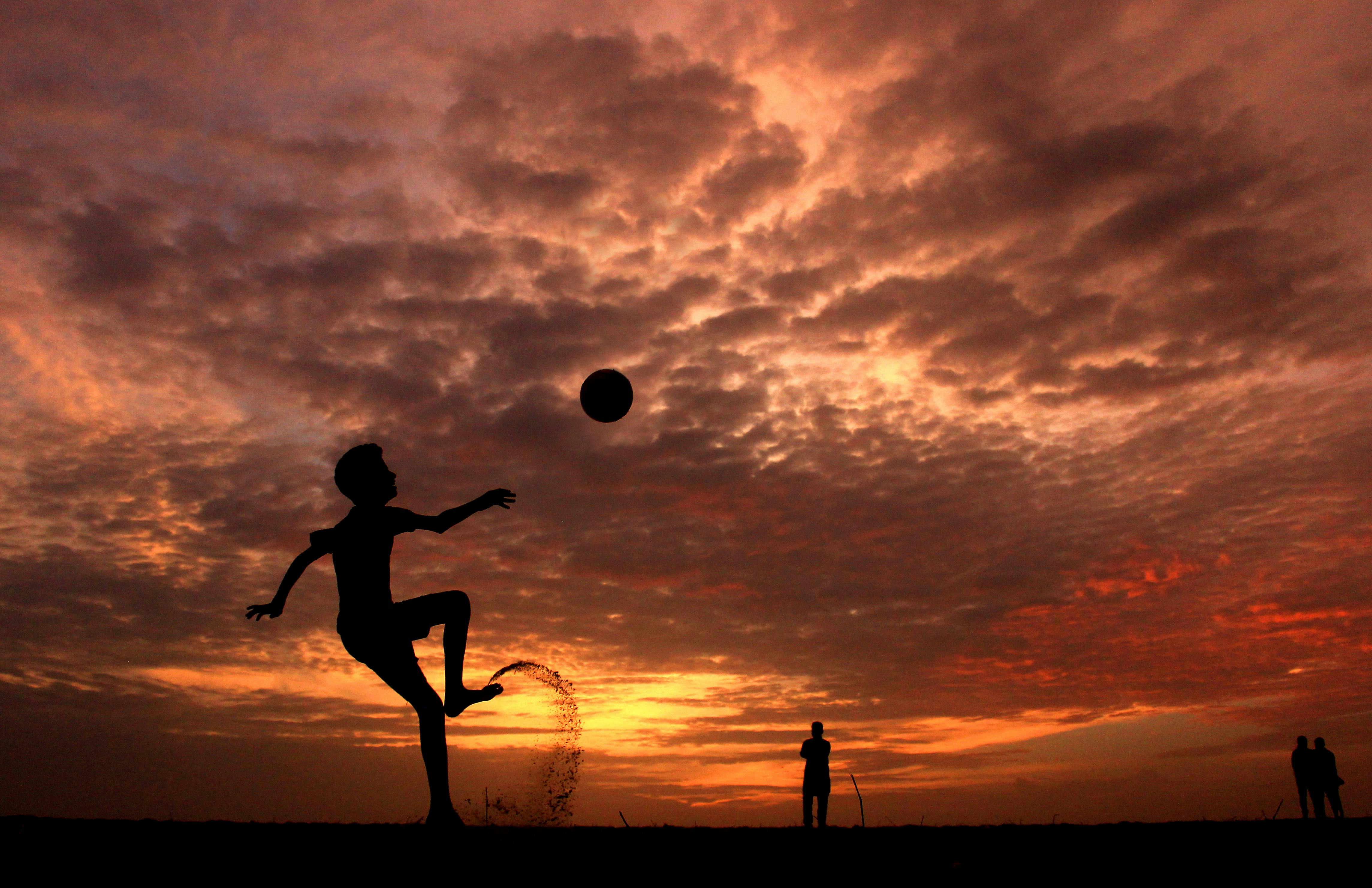Boy Kicking Football at Sunset
