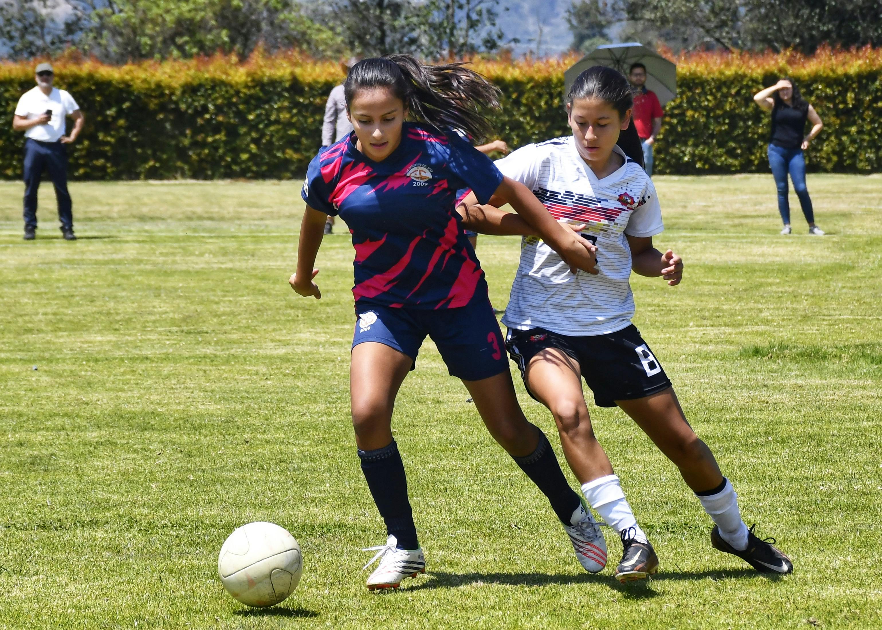 Two Teen Girls Competing for Soccer Ball