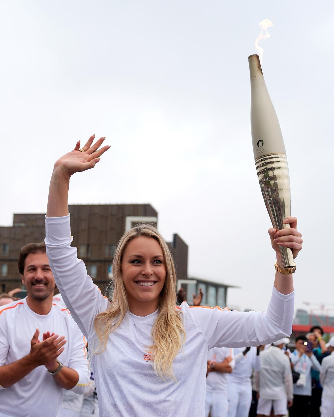 Olympic Torchbearer Waves to Crowd