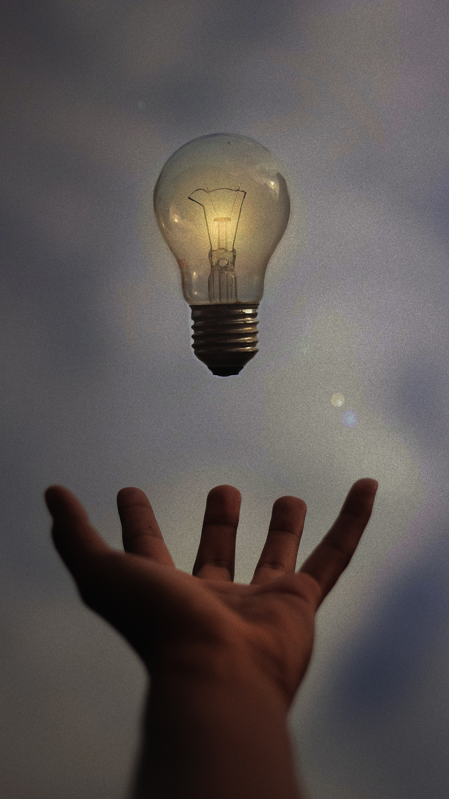 Hand Reaching For Glowing Lightbulb